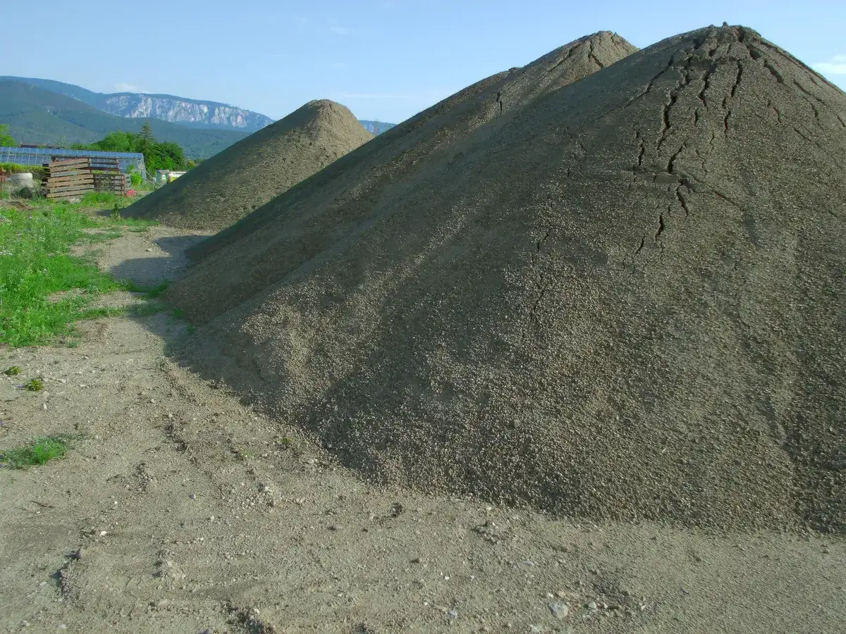 Haufen gesiebte Erde am Lager, im Hintergrund Felder und Berge