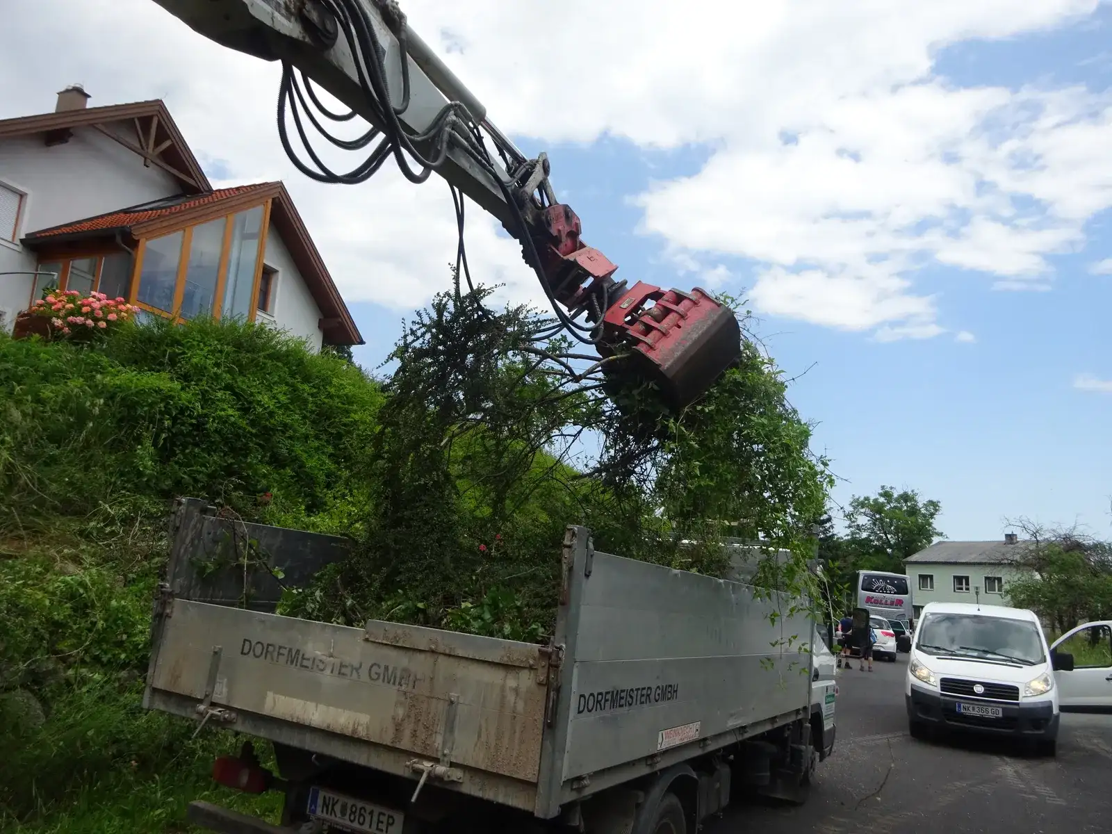 Kranwagen der Dorfmeister GmbH hebt Sträucher aus einem Garten auf die Ladefläche